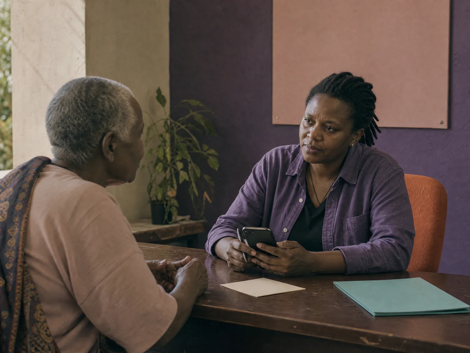 Community service coordinator using a phone while assisting a visitor